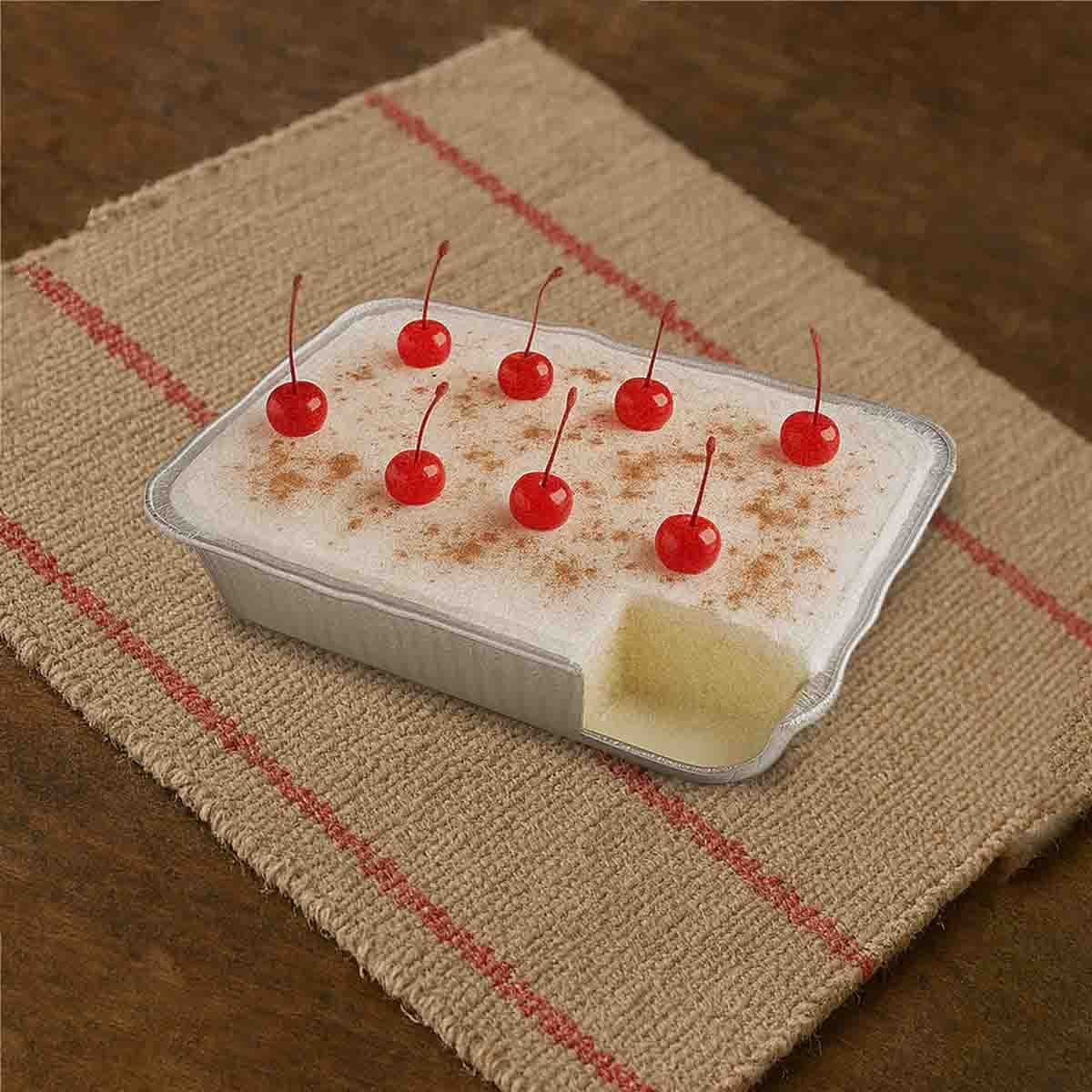 Postre tres leches artesanal con canela y cerezas rojas sobre mantel rústico